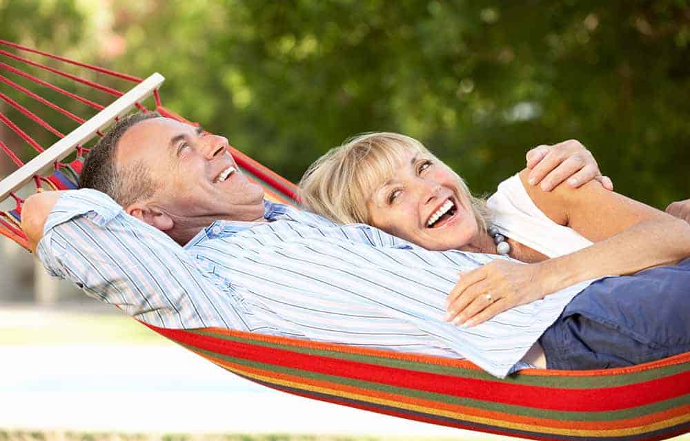 An older retired couple, lounging in a hammock.
