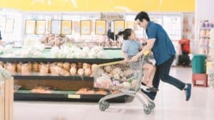 father playing with his daughter pushing the shopping cart