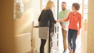 estate agent welcoming a couple to house viewing