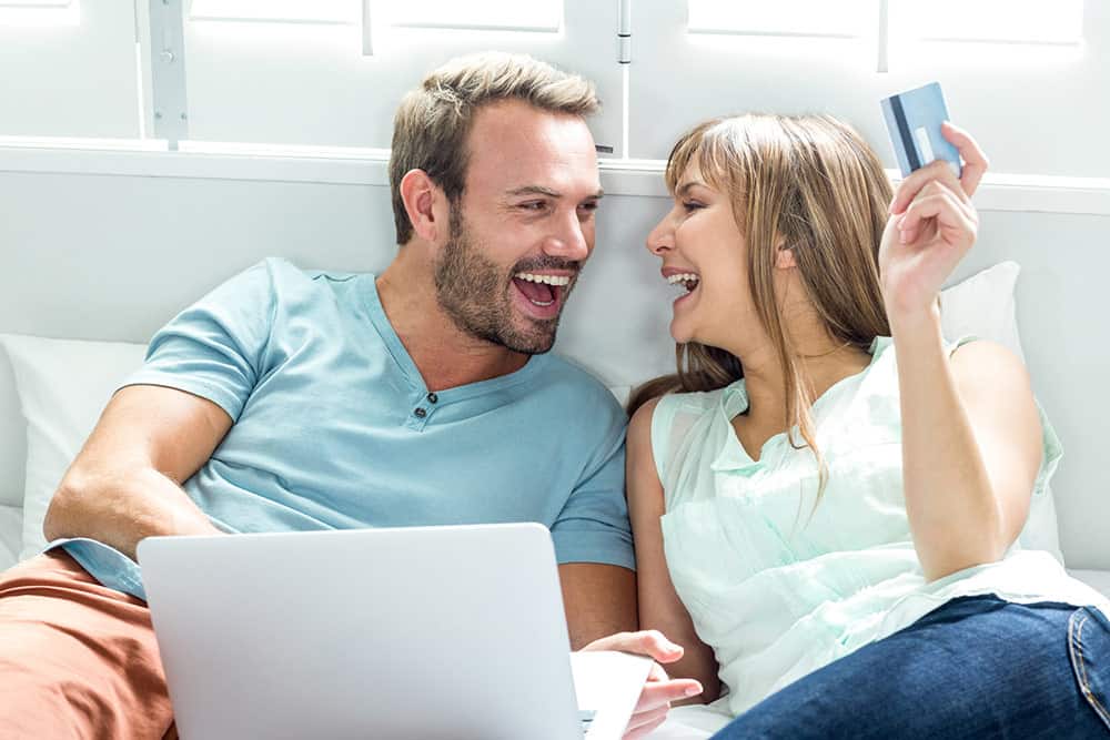 Happy couple with laptop and credit card