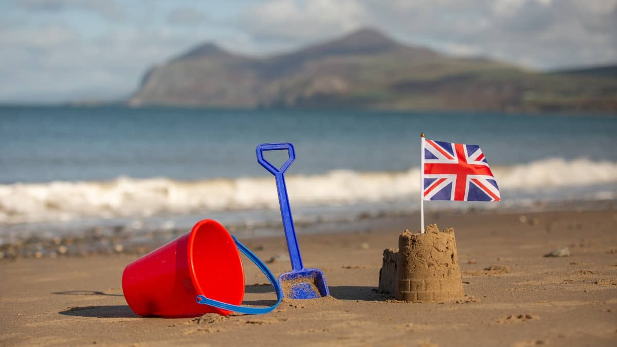 Union Jack flag in a castle shaped sandcastle on a beautiful beach in brilliant sunshine