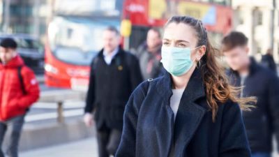 Young woman wearing face mask while walking in the streets of London