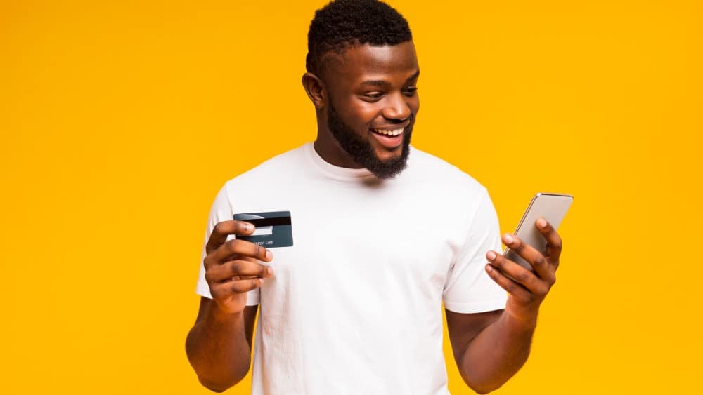 Man using credit card and smartphone for purchasing goods online.
