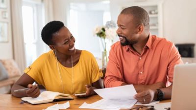 Cheerful mature couple sitting and managing expenses at home.