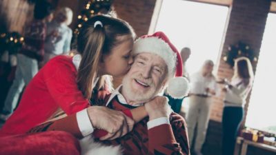 Little girl kissing her granddad at christmastime