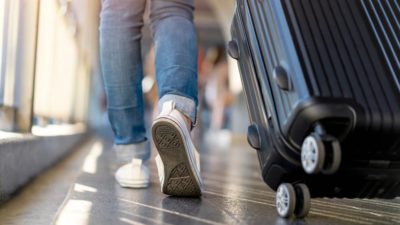 Woman traveller walking alone with suitcase bag.