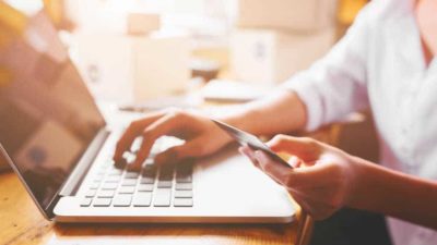 Young woman holding credit card for online shopping at home