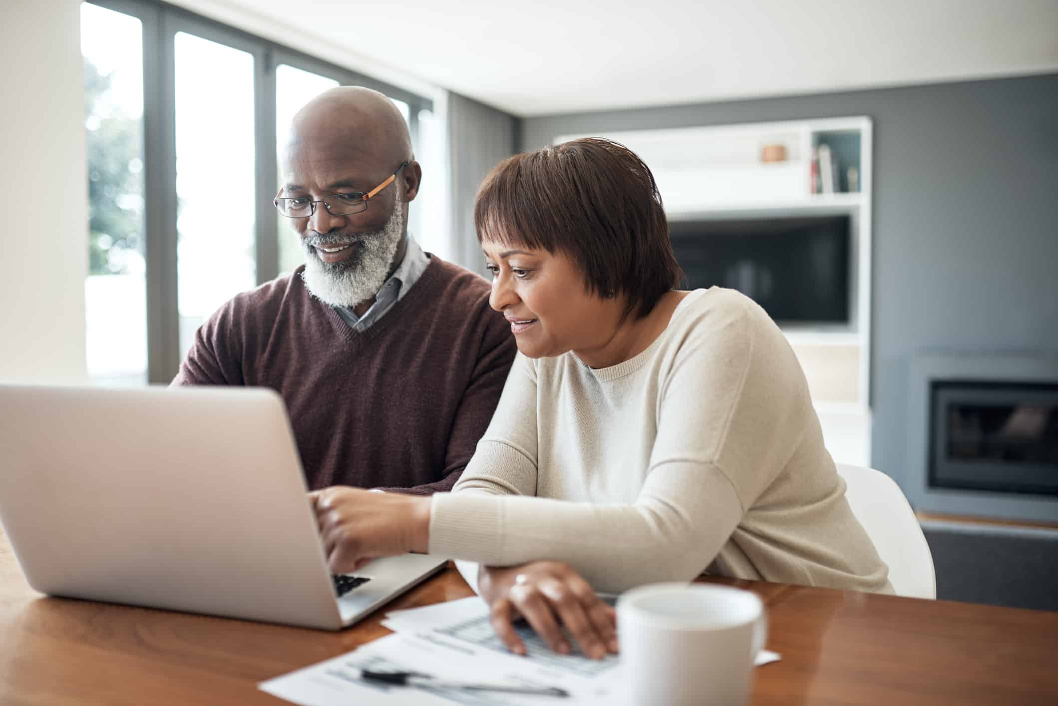 happy senior couple using a laptop in their living room to look at their financial budgets