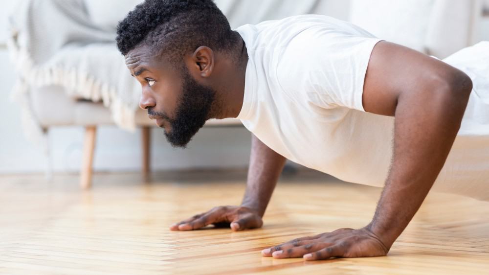 Young man exercising in his house gym, doing push ups