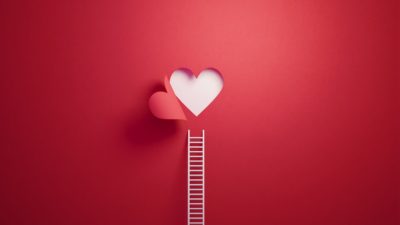 White ladder leaning on red wall with cut out heart shape.