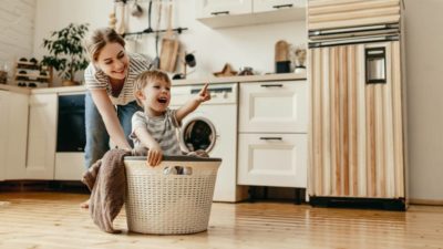 Happy family mother housewife and child son in laundry with washing machine