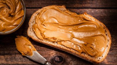 Peanut butter on bread slice shot on rustic wooden table