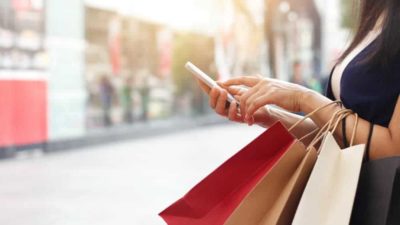 Lady holding mobile phone and shopping bags