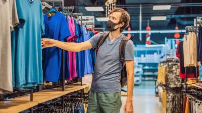 Man in a clothing store in a medical mask because of a coronovirus.