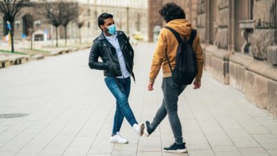 Young people friends meeting in quarantine and greeting without touching their hands