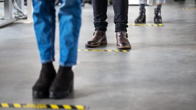 Business people standing behind social distancing signage on office floor