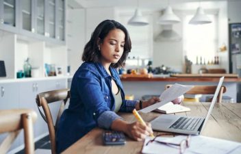 Young woman prioritising her finances at a kitchen table