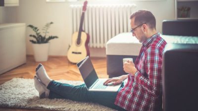 Man drinking coffee and working on laptop