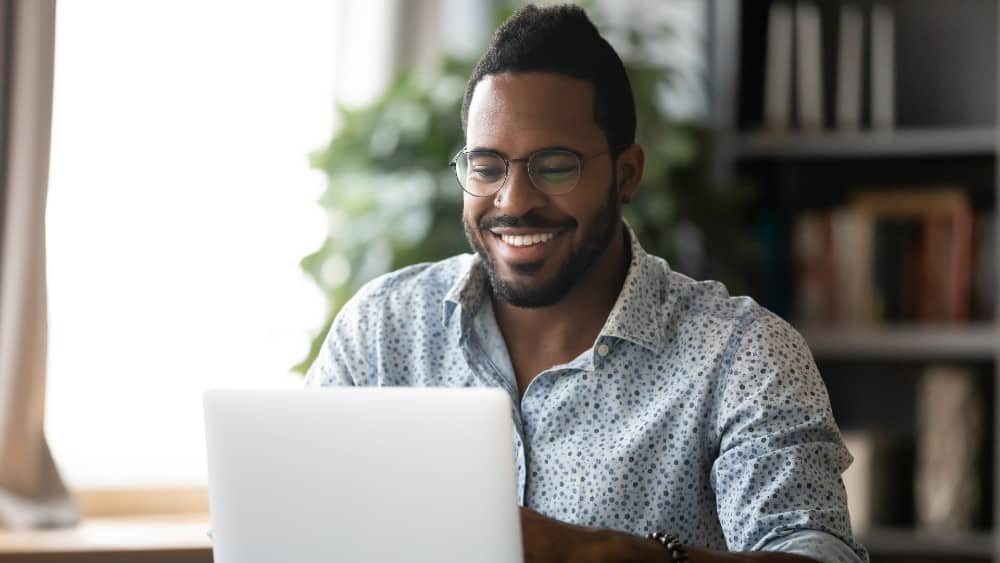 Man smiling and working on laptop
