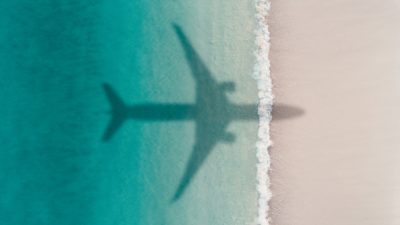 Aerial shot showing an aircraft shadow flying over an idyllic beach
