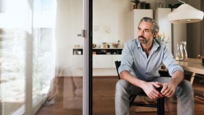 pensive bearded business man sitting on chair looking out of the window