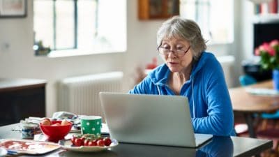 Senior woman wearing glasses using laptop at home