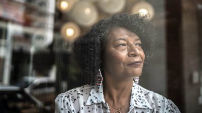 Senior woman looking through the window at home