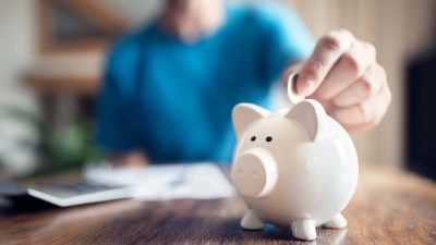 Man putting a coin into a pink piggy bank