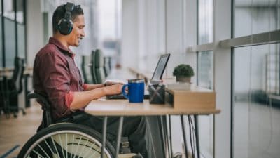 Asian Indian male white collar worker on wheelchair having video conference with his business partners