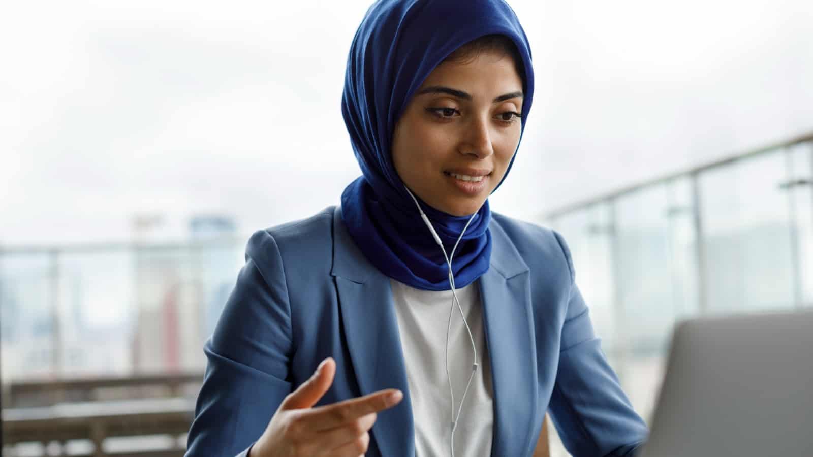 Young woman wearing a headscarf on virtual call using headphones