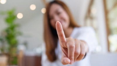 A young Asian woman holding up her index finger