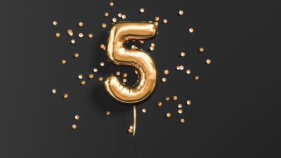 Number 5 foil balloon and gold confetti on black.