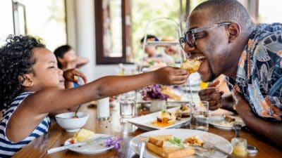 A Black father and daughter having breakfast at hotel restaurant