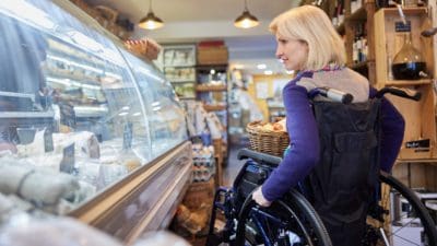 White middle-aged woman in wheelchair shopping for food in delicatessen