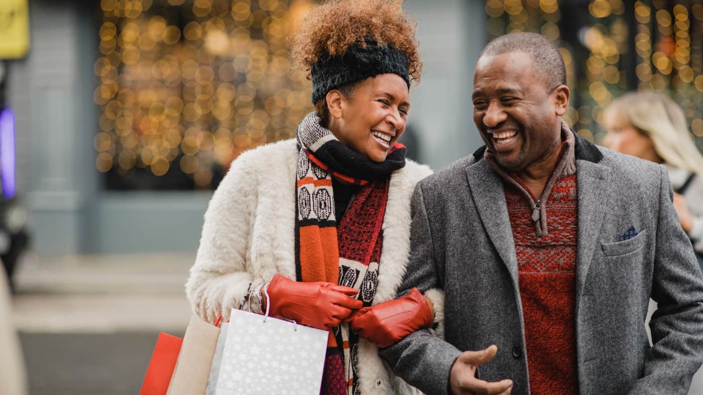 Senior couple crossing the road on a city street. They are walking with shopping bags while Christmas shopping.