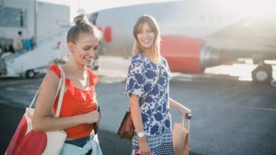Young female couple boarding their plane at the airport to go on holiday.