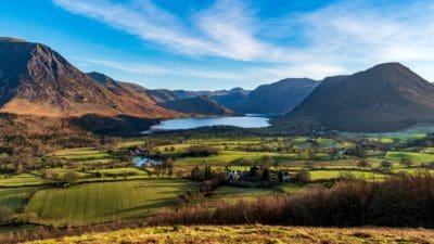 View of Lake District. English countryside with fields in the foreground and a lake and hills behind.