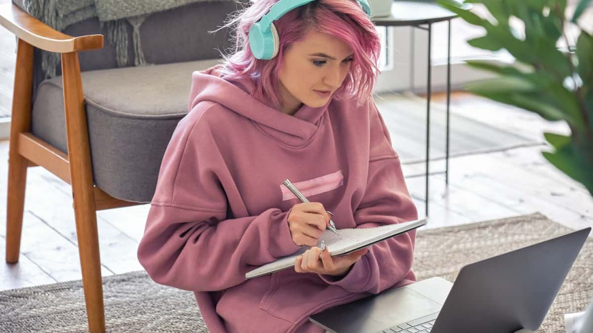 Young Caucasian woman with pink her studying from her laptop screen