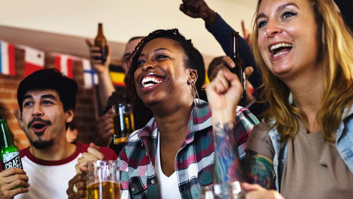 Diverse group of friends cheering sport at bar together