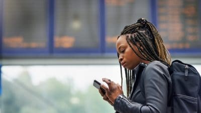 Young black woman using a mobile phone in a transport facility
