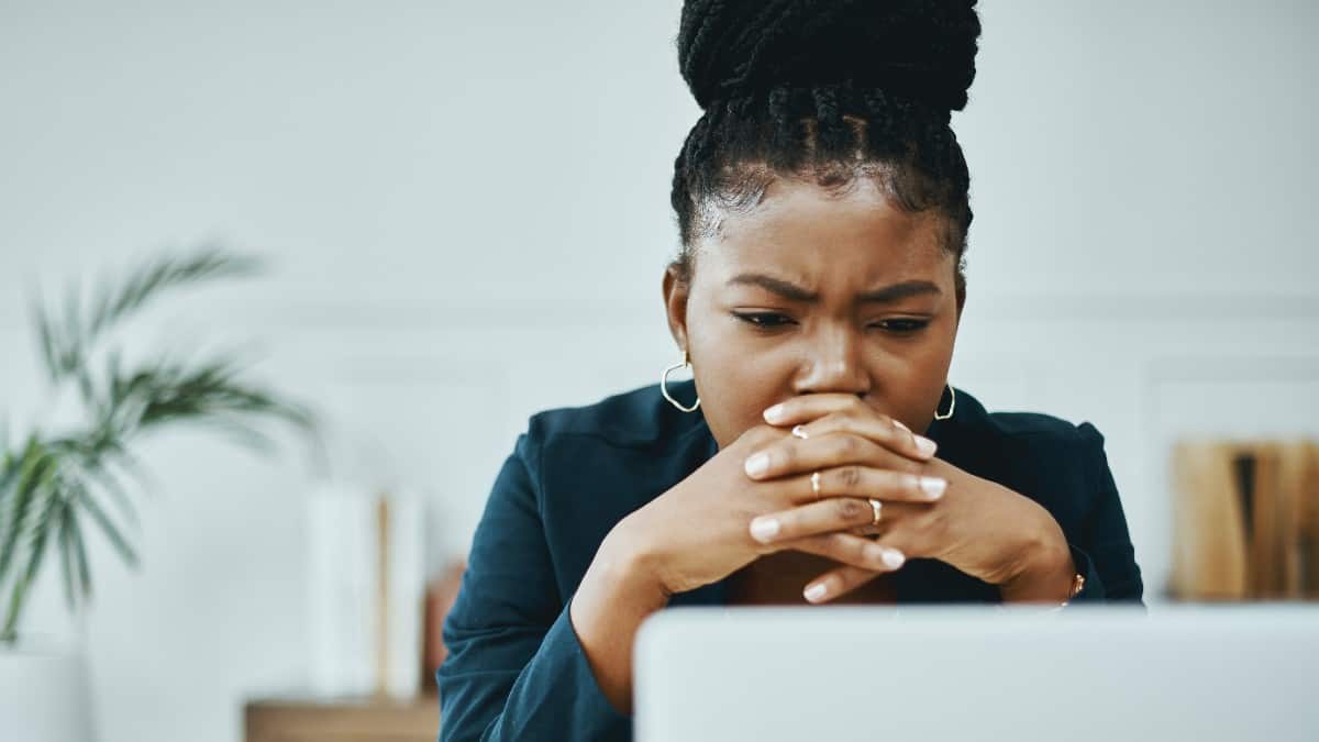 Young Black woman looking concerned while in front of her laptop