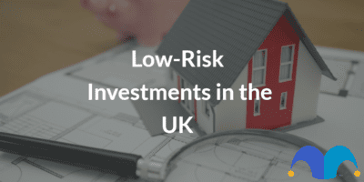 Miniture home sitting on blueprints with the text “Low-Risk Investments in the UK” and The Motley Fool jester cap logo