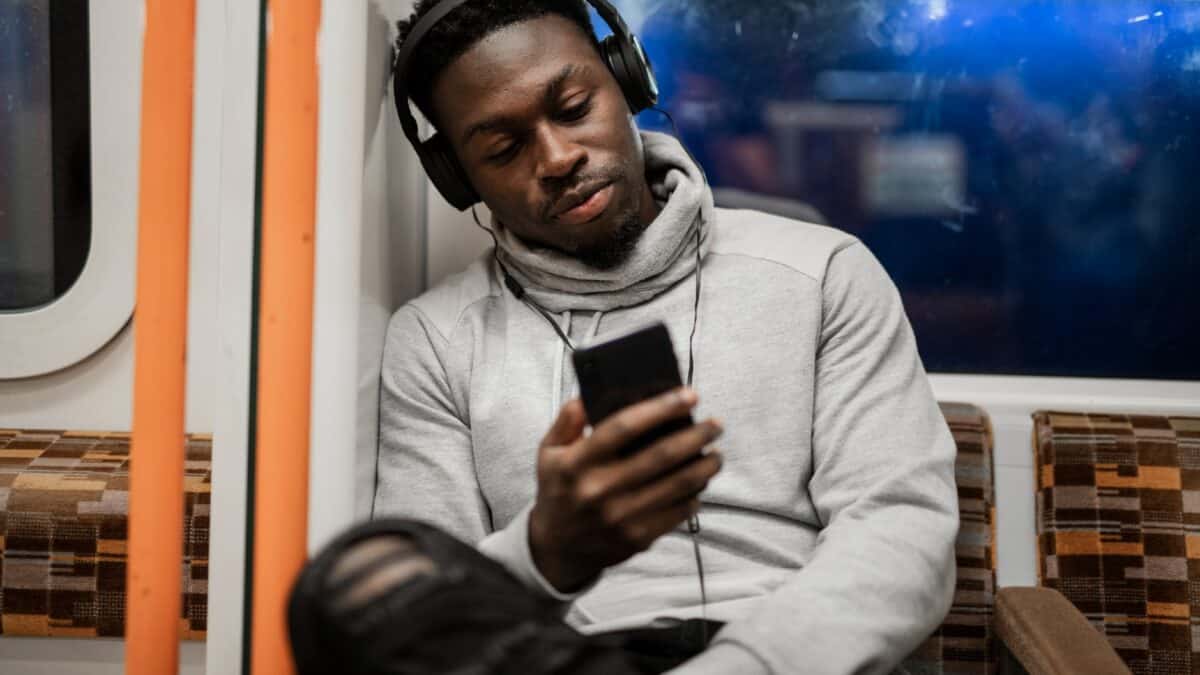 Νεαρός μαύρος που κοιτάζει το τηλέφωνο ενώ στέκεται στο Υπέργειο του Λονδίνου