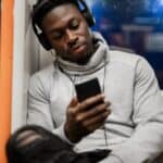 Young black man looking at phone while on the London Overground