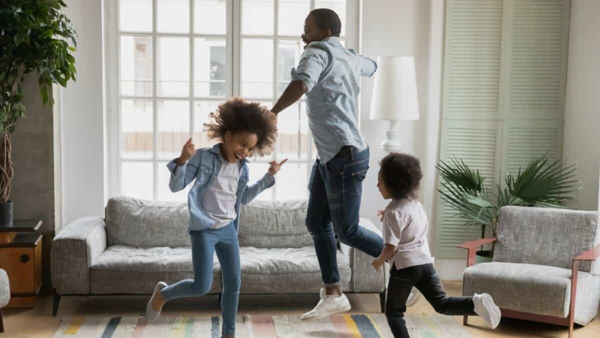 Black father and two young daughters dancing at home