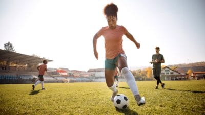 Young black female footballer training on stadium pitch